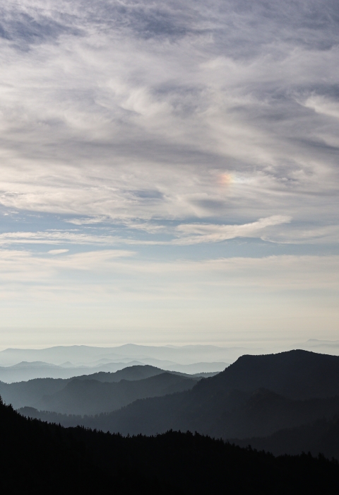 Rolling, forest-covered mountains beneath a partly cloudy sky