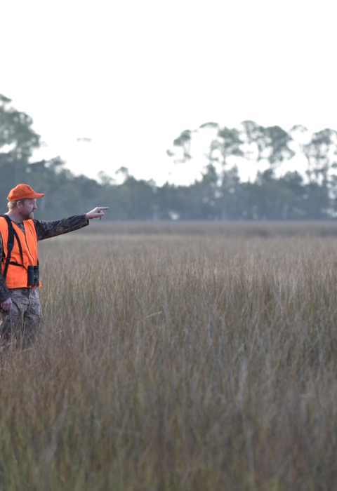 Two hunters in orange hunter outfit standing in the field.