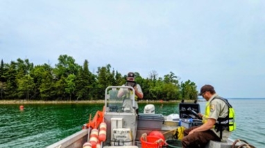 Two employees holding devices on a boat