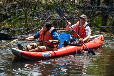 Service intern, Suzena Arias, and employee rafting through wetland to check minnow traps