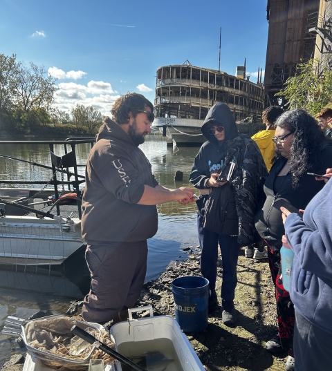 Image of USFWS staff next to boat showing fish to students.