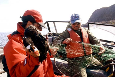 2 people in a boat with a surf scoter in hand