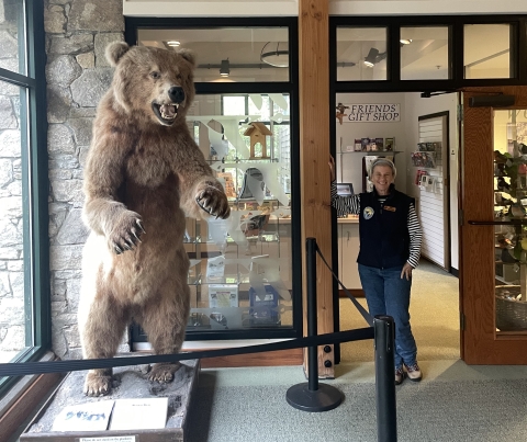 volunteer smiling next to taxidermy grizzly bear