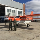 2 people stand in front of an airplane