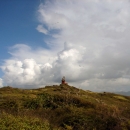 A lighthouse at the top of a hill overlooking a body of water