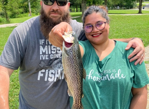 A couple posing with a Rainbow trout
