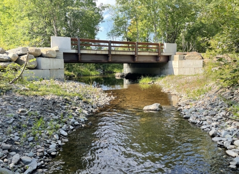 newly constructed bridge rests atop concrete blocks to cross the river 