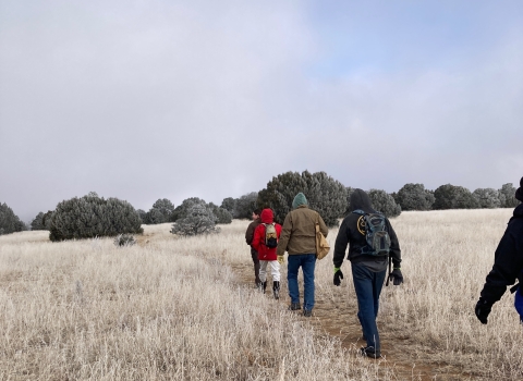 Hikers in warm clothes hiking the Juniper Trail led by a refuge ranger.
