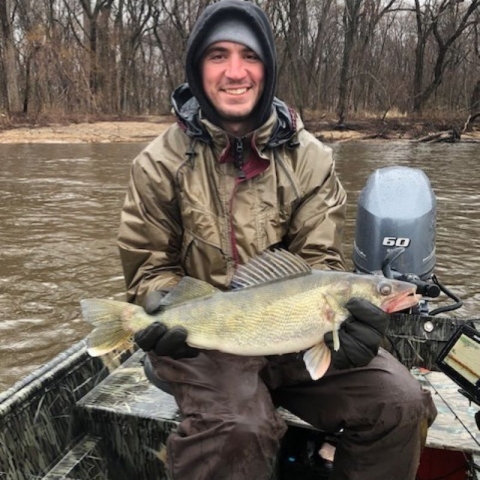 Man sitting on boat holding big fish.