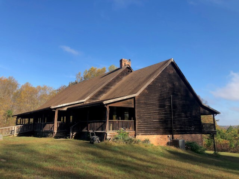 a brown lodge structure with steep roof on a grassy hill 