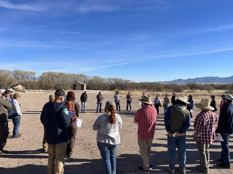 Group of individuals stand discussing on a field