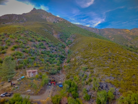 Aerial image of a gully on a mountainside and construction equipment parked near a rock wall