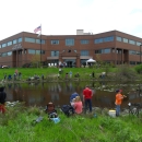 People fishing on a pond in front of a large brick building. Text on building U.S. Fish and Wildlife Service