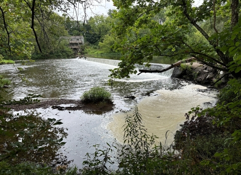 A view of a dam and river surrounded by trees.