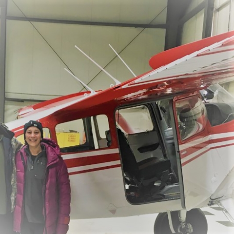 a woman by a plane in a hangar