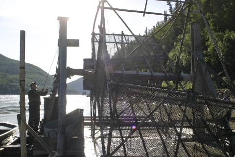 a man standing on a fish wheel platform in a large river