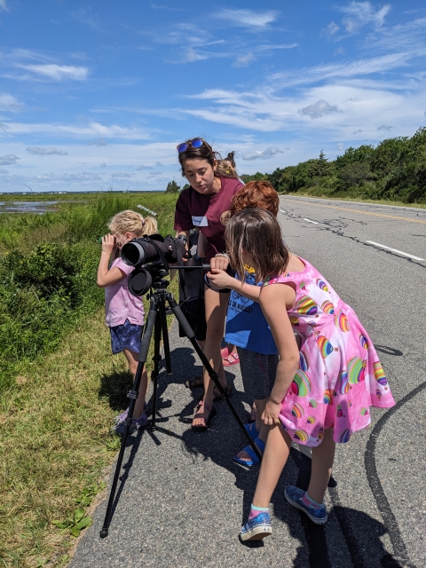 Children look through scope into marsh