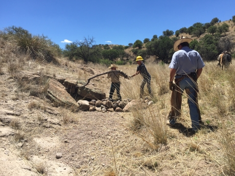Individuals work on installation in a field with rocks