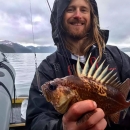 a man with long hair holding a spiky fish