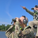 2 men sitting in boat using binoculars, using headphones