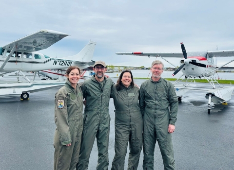 four pilot biologist in front of two planes