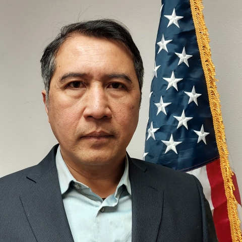 Head and shoulders of man in front of American flag
