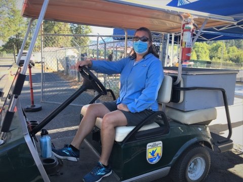 USFWS volunteer transports fertilized salmon eggs in a golf cart from the spawning area to the nursery.