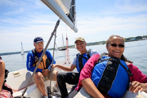 Group of smiling adults enjoy a beautiful day sailing on the bay