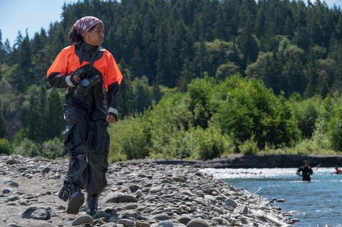 USFWS digital media intern, Typhanie Shepherd, walking along the Elwha River with a video camera