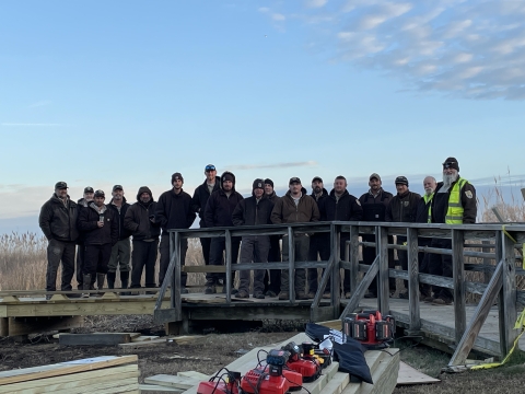 a group of people stand on a boardwalk during a construction project