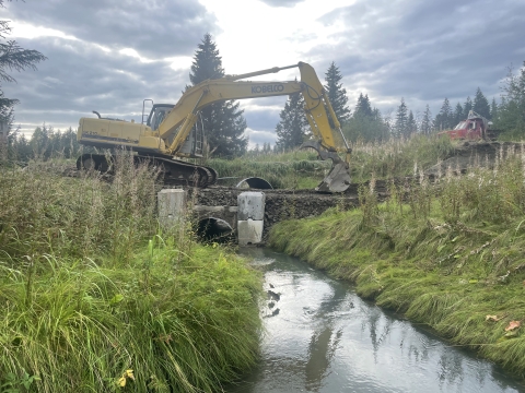 excavator readies ground around a bridge foundation over a river