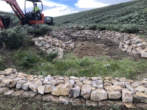 short rock wall with heavy equipment in background