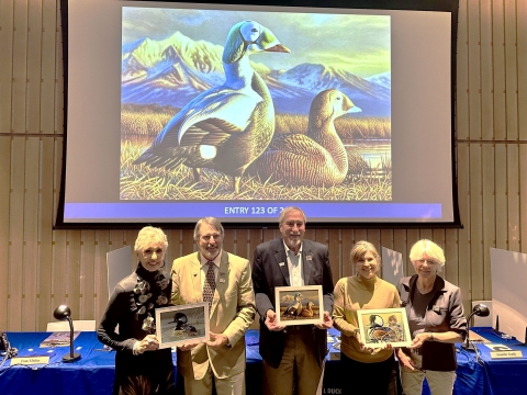 Judges at the 2024 Federal Duck Stamp Art Contest hold the winning artwork.