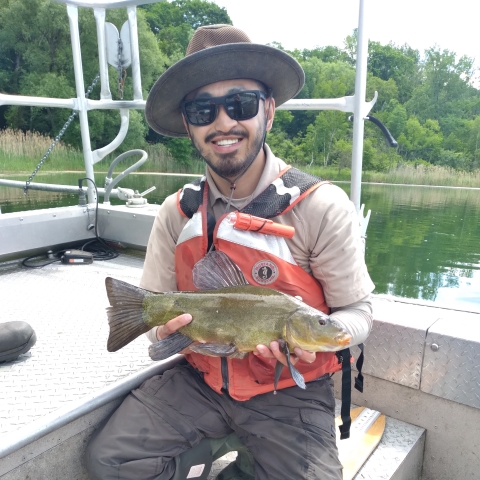 Image of biologist holding a fish in a boat.