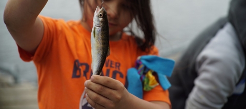 a young girl holding a fish
