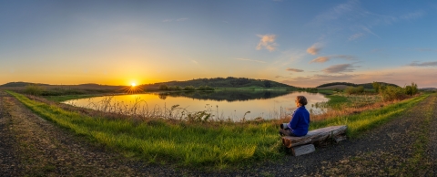 Woman sitting on bench overlooking lake.