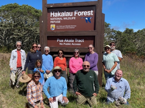 A group of volunteers in front of the brown Hakalau Forest sign