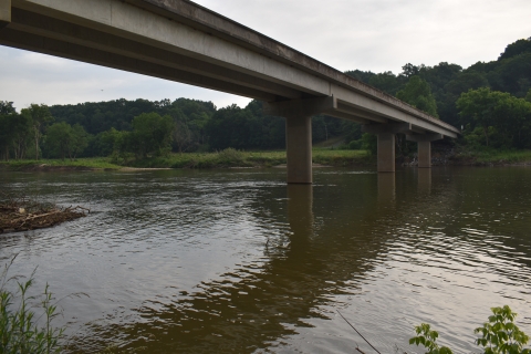The Nolichucky River flows under a bridge. The water is vary brown due to suspended sediment. 