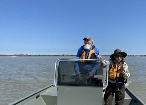 Two Service biologists stand in a boat near the coast of Texas.