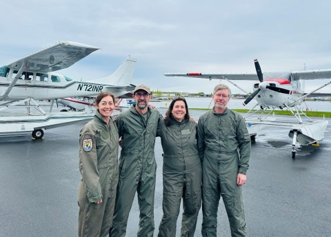 four pilot biologist in front of two planes