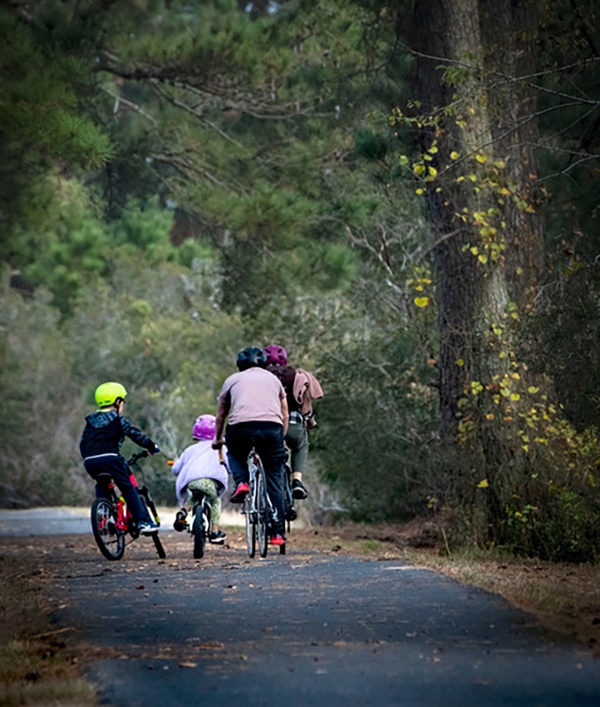 A family bikes along a wooded trail