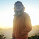 man with mountains and sun in the background