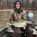 Man sitting on boat holding big fish.