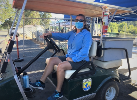 A USFWS volunteer drives a golf cart carrying fertilized spring Chinook salmon eggs from the spawning area to the nursery.