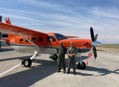 two people standing in front of an airplane