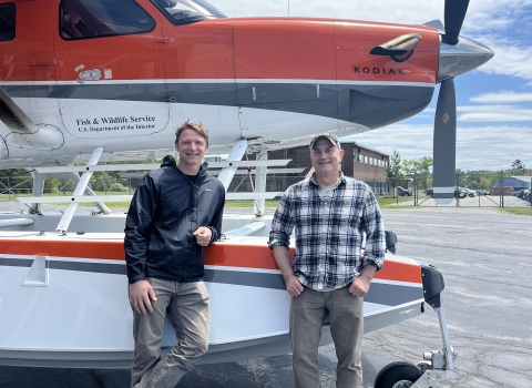 two pilot biologists standing by a plane